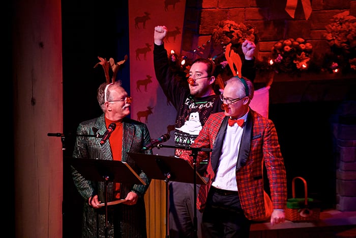 Photo from the event of three festively dressed men wearing bright red Rudolph noses and headbands with antlers on them.