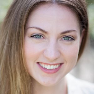 A smiling young woman with green eyes and light brown hair.
