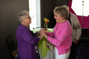 Photo from the Gala of two women clasping hands and talking together.