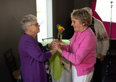 Photo from the Gala of two women clasping hands and talking together.