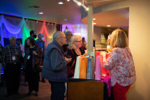 Photo from the gala of the New Stage Theatre's lobby, colorfully decorated and lit with attendees talking across the concessions bar.