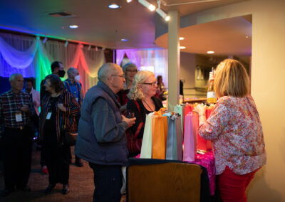 Photo from the gala of the New Stage Theatre's lobby, colorfully decorated and lit with attendees talking across the concessions bar.