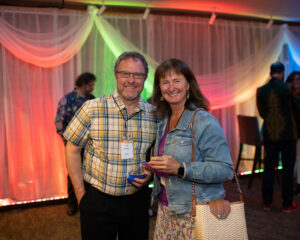 Photo from the Gala in the theatre lobby of two attendees, a man and woman, standing side by side smiling brightly for the camera.