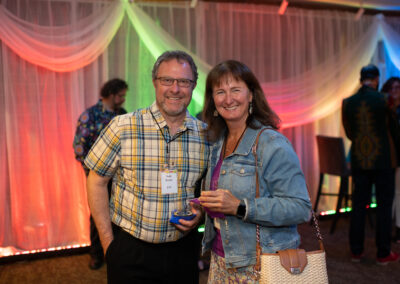 Photo from the Gala in the theatre lobby of two attendees, a man and woman, standing side by side smiling brightly for the camera.