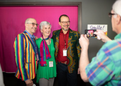 Photo from the Gala of a man using a smart phone to take a photo of three other brightly dressed attendees.