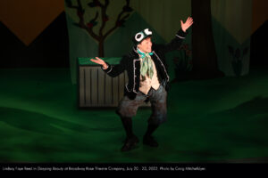 Frankie the Song-and-Dance Frog dances center stage in a green velvet coat and introduces the audience to the story of Sleeping Beauty.