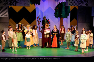 King Charles (Jesse Cromer) and Queen Lily (Kira Batcheller) hold their newborn Princess Penelope as the people of their kingdom look on adoringly.