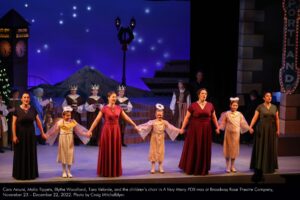 Cara Arcuni, Malia Tippets, Blythe Woodland, Tara Velarde, and the children's choir in "A Very Merry PDX-mas" at Broadway Rose Theatre Company, November 23 - December 22, 2022. Photo by Craig Mitchelldyer.