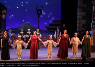 Cara Arcuni, Malia Tippets, Blythe Woodland, Tara Velarde, and the children's choir in "A Very Merry PDX-mas" at Broadway Rose Theatre Company, November 23 - December 22, 2022. Photo by Craig Mitchelldyer.