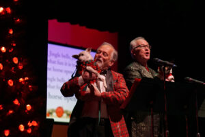 Broadway Rose staff and family singing a song with the cute dogs at the microphones.