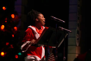 Broadway Rose cast members dressed in festive clothes sing songs for the crowd of kids and families.