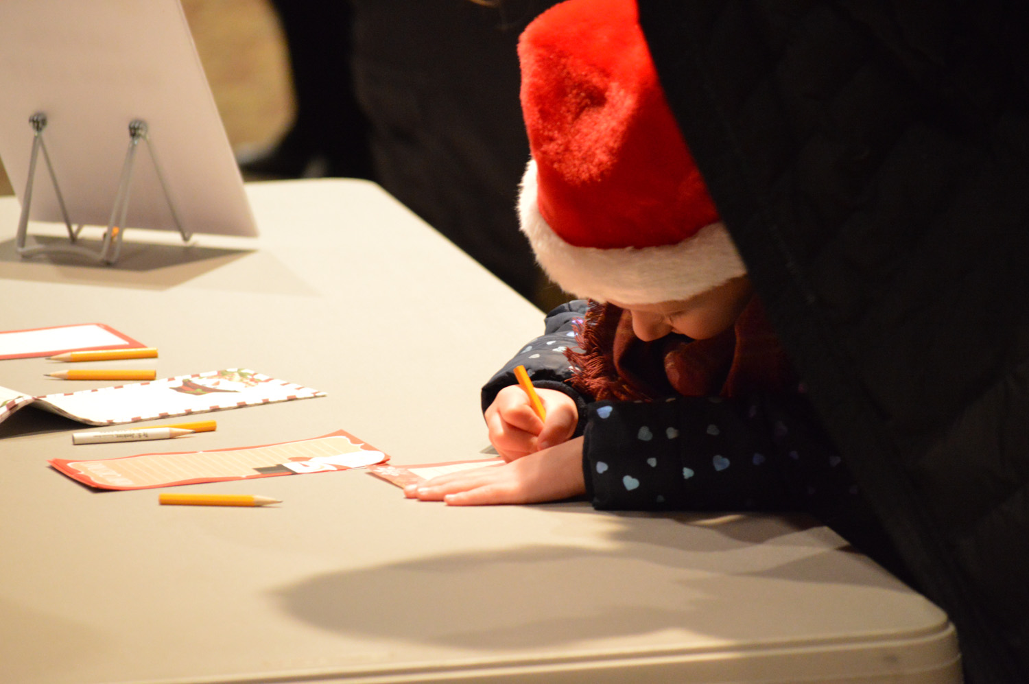 A girl writing down her Christmas list for Santa.