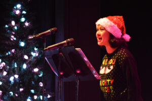 Broadway Rose cast members dressed in festive clothes sing songs for the crowd of kids and families.