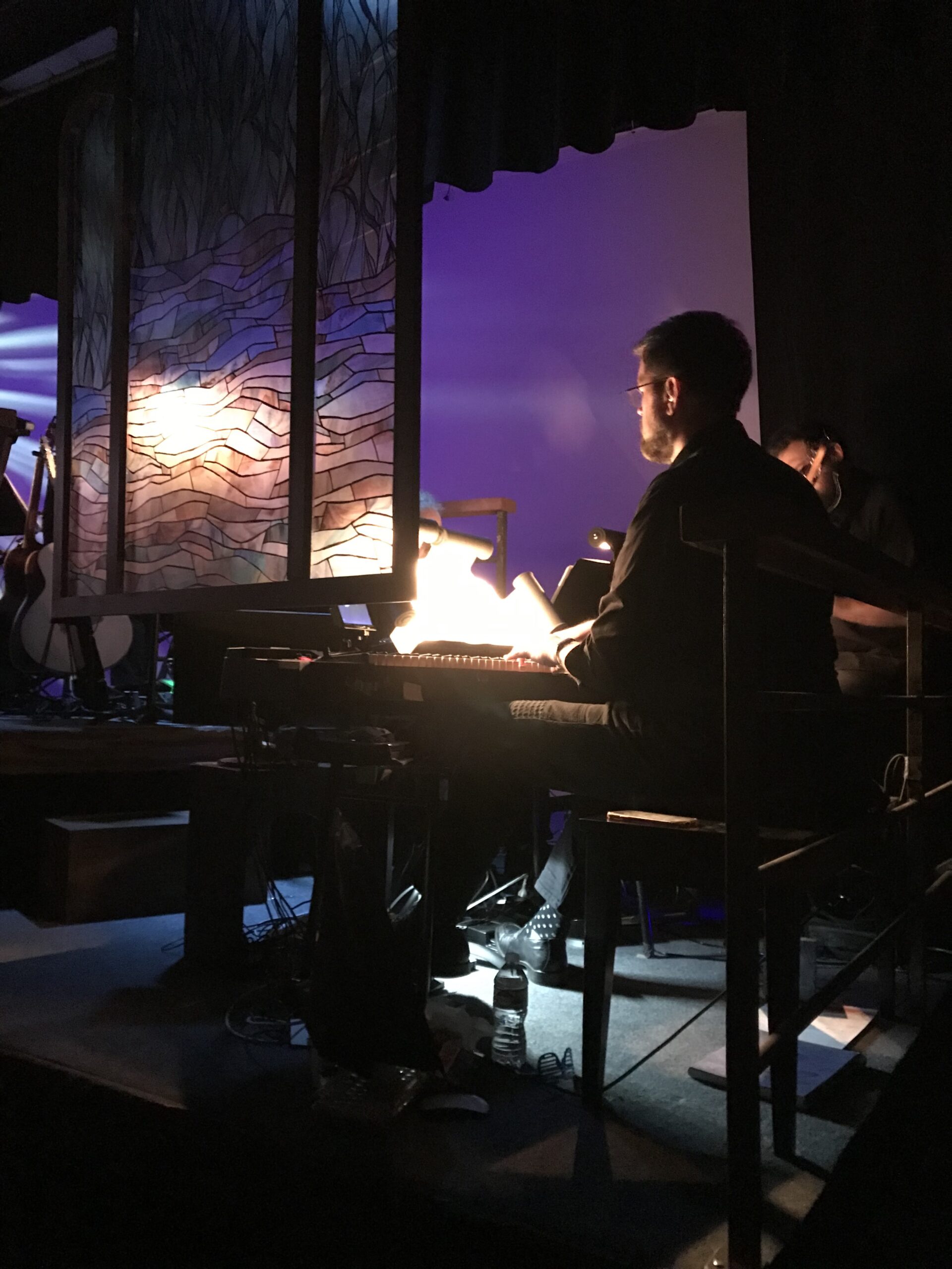 Photo of Alan Lytle at the piano, conducting the orchestra on stage for Footloose (2019).