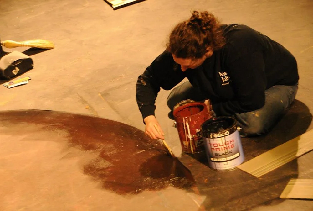 Photo of Kristeen Willis painting a set floor.