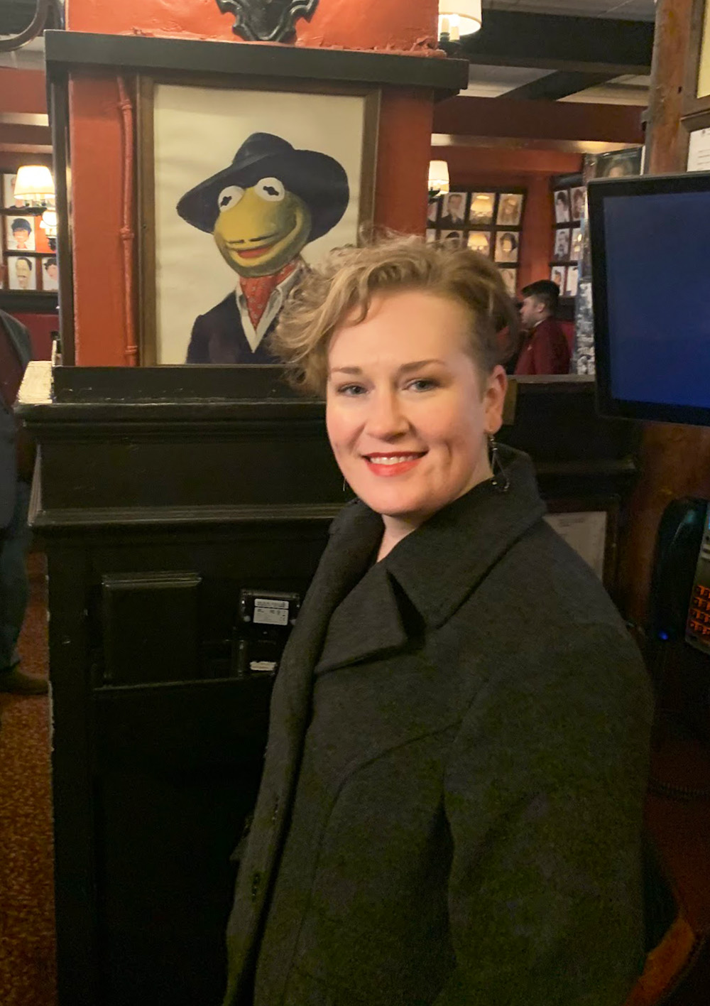 Holly and Kermit Photo of Holly at Sardis Restaurant in New York, standing next to a portrait of Kermit the Frog.