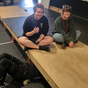 Summer interns securing a platform on stage.