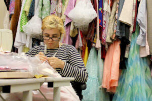 Photo of a costume shop intern hand-stitching a costume piece.