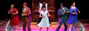Production photo from Ain't Misbehavin', showing the whole cast across the stage, dancing in unisons around the upstage piano.