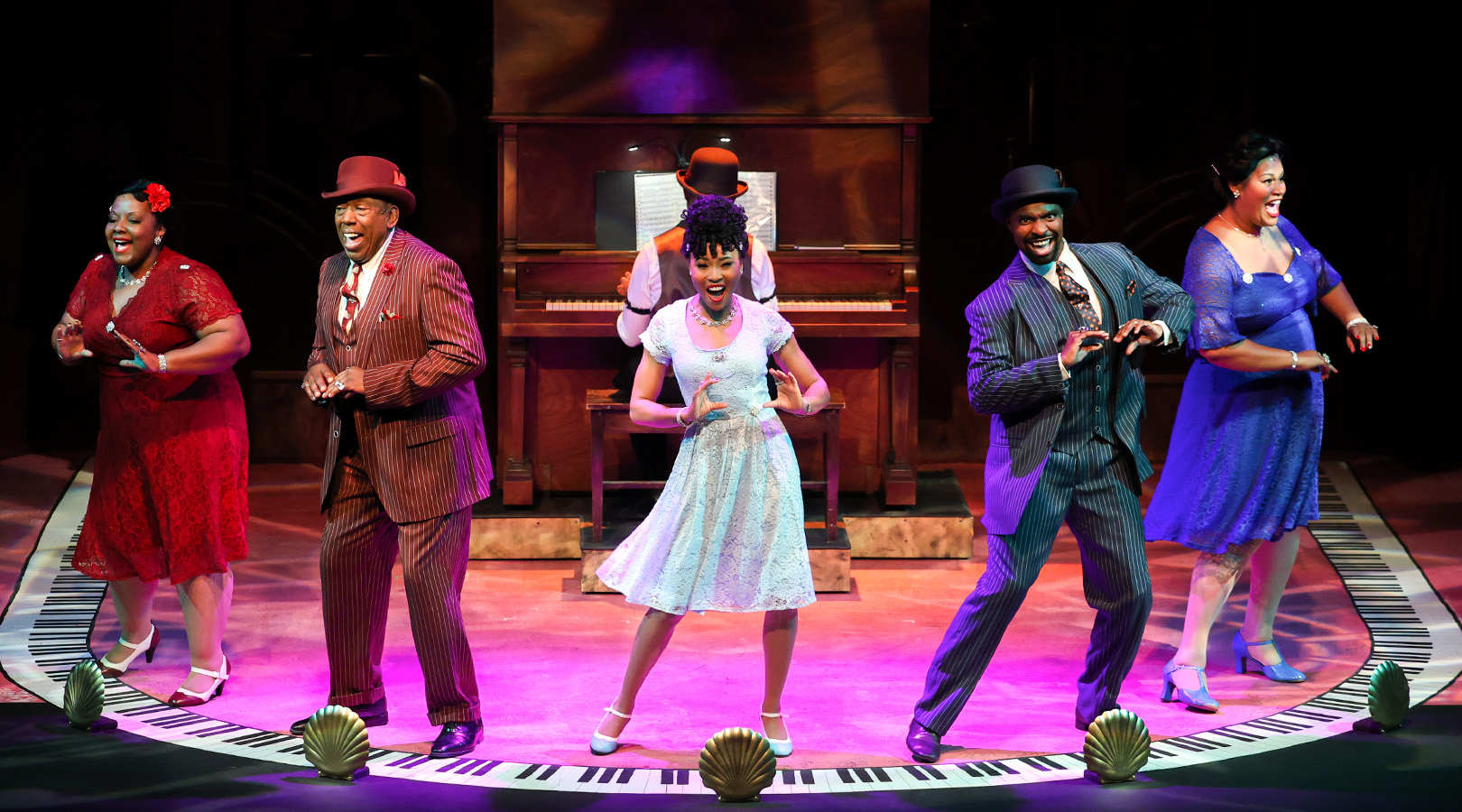 Production photo from Ain't Misbehavin', showing the whole cast across the stage, dancing in unisons around the upstage piano.