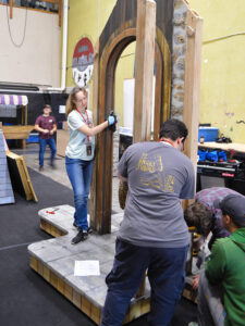 Photo of interns back stage constructing a faux stone doorway for the 2023 production of Cinderella.