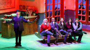 Photo of the cast of Home for the Holidays singing out to the audience from the bus station bench.