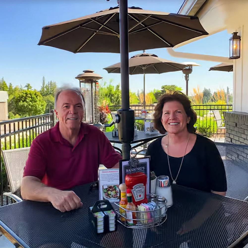 Photo of Mark and Trish Banning on the patio of Banning's Restaurant on a bright summer day.