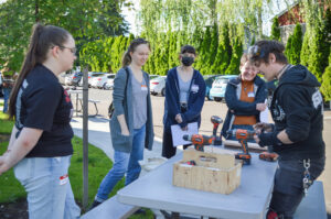Photo of some of our latest interns, gathered around a table where our technical director, Raef Wheaton, demonstrating some of the differences between types of power drills.