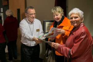 A photo of Broadway Rose volunteers and patrons greeting each other at the theatre house entrance, smiling and ready to see a show.