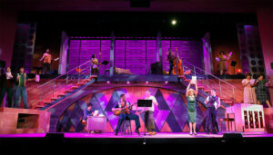 Photo of our recent 2024 summer production of Beautiful The Carole King Musical, one of our biggest shows ever. The photo shows a moment from the song 1650 Broadway when the ensemble is spread across the whole stage stage, up on raised platforms, and dancing to a medley of 1950s hits.