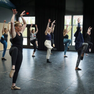 Photo from a Broadway Rose dance class showing our adult students during a short dance routine, their arms in the air and their right legs kicked up high.
