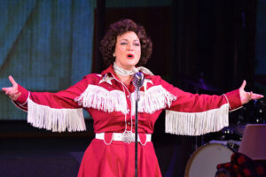 Photo of Sara Catherine Holder as Patsy Cline in her iconic red cowgirl outfit.
