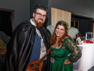 Photo of Brian Karl Moen and his wife Andrea at our 2023 Once Upon a Time Gala. They are dressed in medieval garb, Brian as a minstrel and Andrea as a green fairy. They are smiling for the camera.