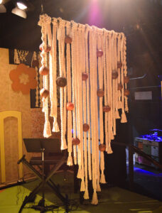 Photo of one of the macramé sections of the set for 8-Track. It is made of thick rope and huge wooden spheres, like a blown-up version of the real thing.