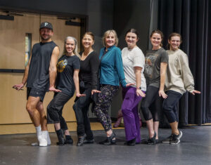 Photo of the students and teacher in our most recent dance class. THey are all posing together in a contraposto, one leg straight and the other bent position. Their hands are out to their sides, flat, like a jazz dance move.