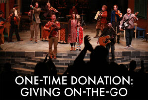 Photo from our production of Once showing the audience standing and cheering at the end as the cast sings the final song. Words are superimposed over the top of it that say One Time Donation, Giving on the go.