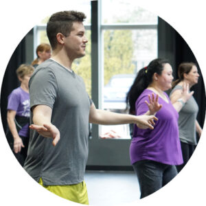 Photo from one of our adult tap classes showing students with their arms out and looking forward toward the mirrors to check their work.