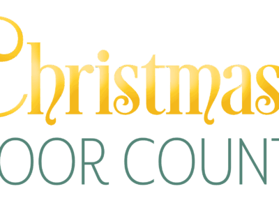 Logo for Christmas in Door County. Christmas is in golden, curly lettering, while In Door County is in a forest green colored, plain, unflourished font.