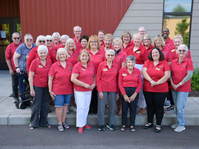 Photo of our 2025 guild, taken outside the rehearsal hall of the Broadway Rose New Stage theater. There is nearly two dozen people all smiling for the camera.
