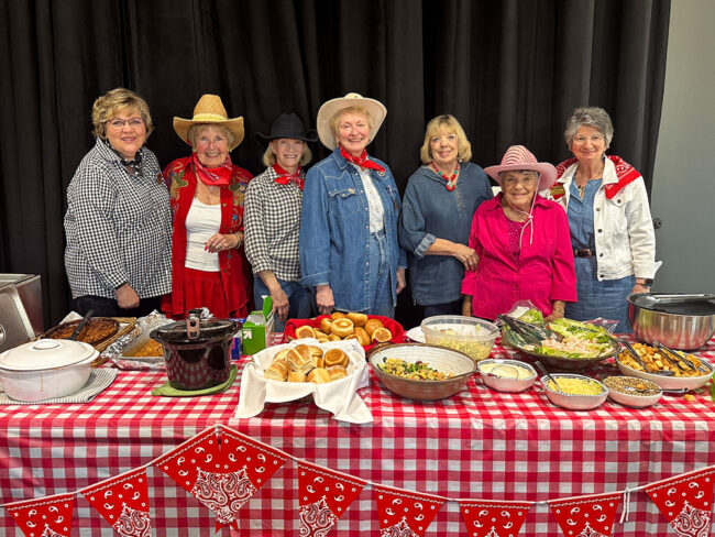 Photo from a guild-hosted Broadway Rose staff barbecue. The guild is dressed in fun cowboy themed outfits and serving up barbecue to hungry Broadway Rose staff members.