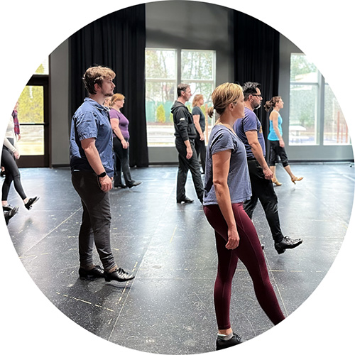 A photo from one of our adult tap beginners class showing many students holding out one foot, ready to take their first steps in tap dancing.