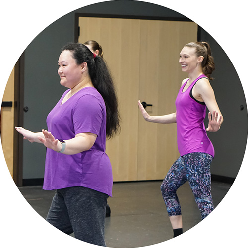 A photo from one of our adult tap classes showing two women in purple and pink posing while doing a tap routine.