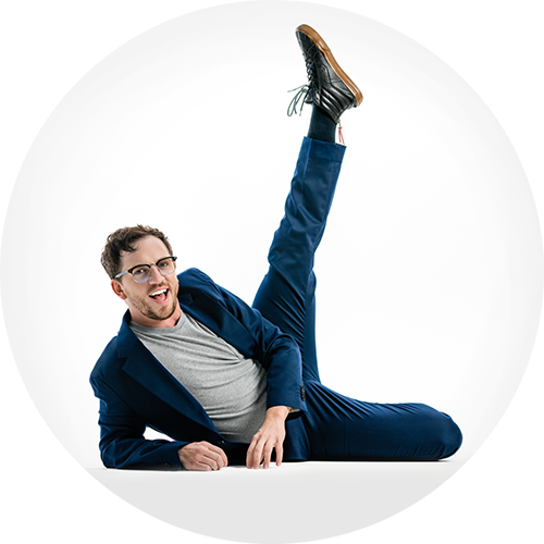 Photo of Daniel Switzer lying on the floor with one foot kicked high into the air.