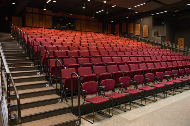 Photo of the seating at the New Stage, showing the widened stair cases, hand rails, and wheelchair accessible front row.