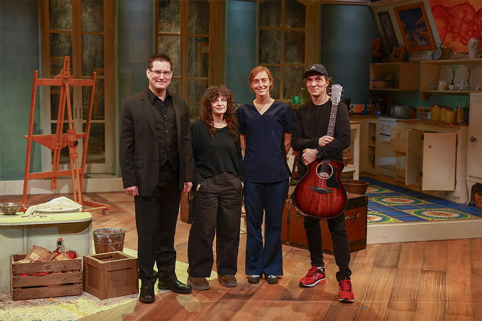 A photo of the band all together on the set of In Clay. They are all dressed in black and smiling for the camera.