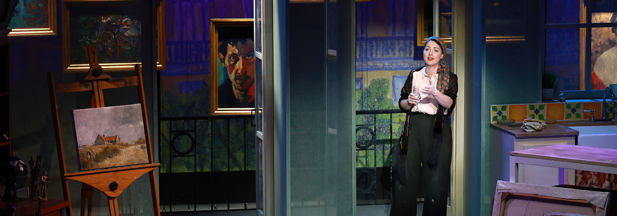 A photo of Malia Tippets in In Clay. She is standing by tall French patio doors on the back wall of the set, designed as a Parisian apartment in the 1930s.