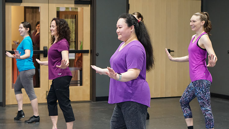 Tap - Intermediate A photo from one of our adult tap classes showing two women in purple and pink posing while doing a tap routine.