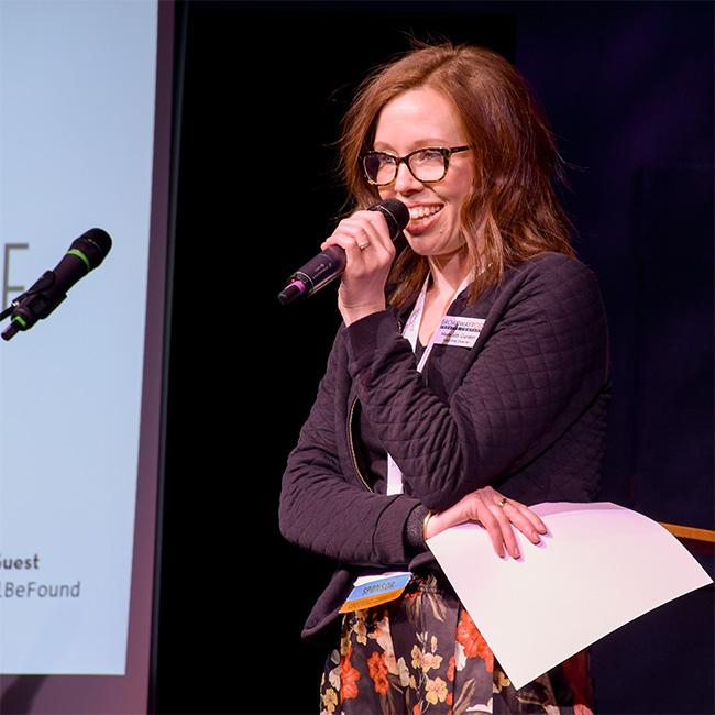 A photo of our executive director Meredith Gordon on stage speaking to the crowd at this spring's NAMT conference.