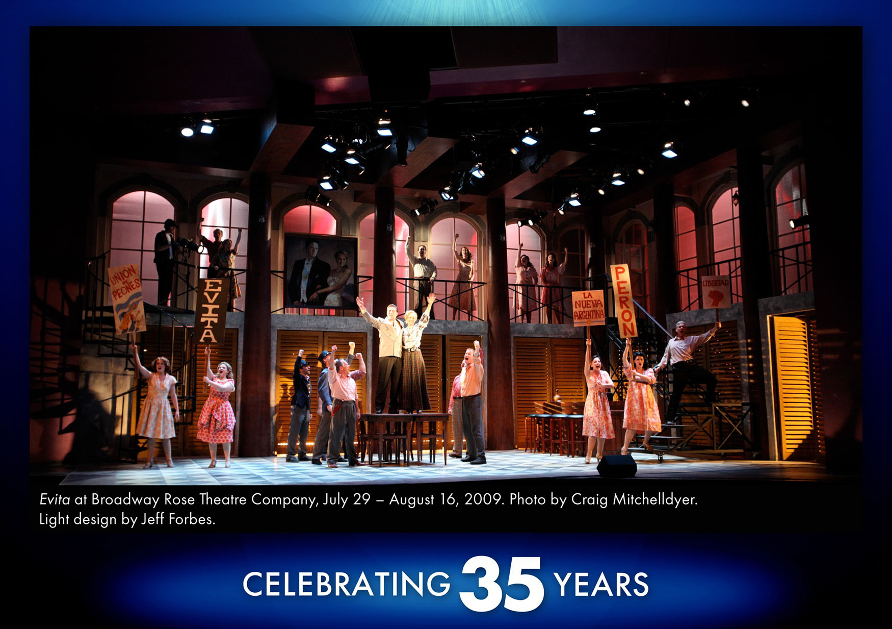 Spotlight 10 A photo from our 2009 production of Evita. The set depicts the exterior of a luxurious villa with large arched windows, but with a street or alley right in front of it, juxtaposing the rich and the poor. Lights bathe the stage in wonderful and unexpected places like warm pinks from inside the large mansion windows, or bright white spots pointing directly down from the ceiling. The lighting is dramatic and exceptional.