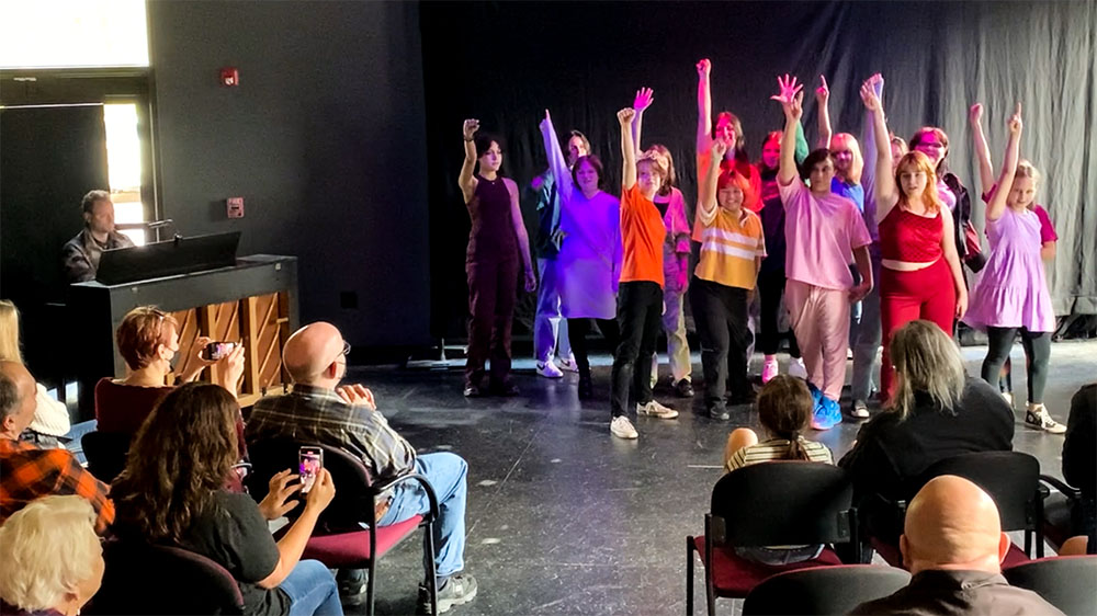 A photo from our teen cabaret showing a group of about a dozen teenagers posing at the end of a song in front of a group of friends and family.